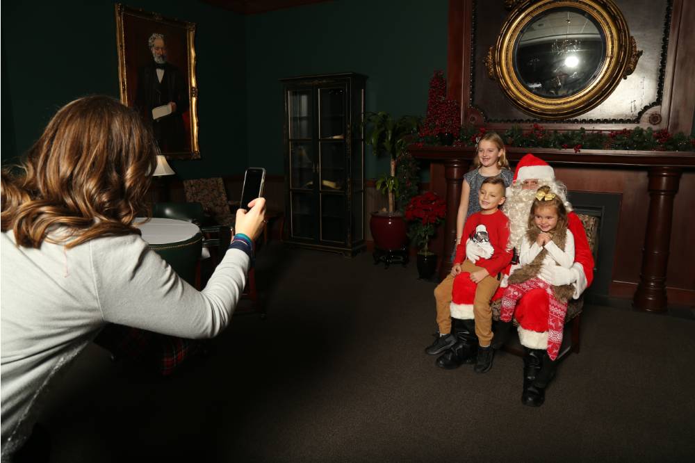Alumni taking picture of her three kids with Santa Claus